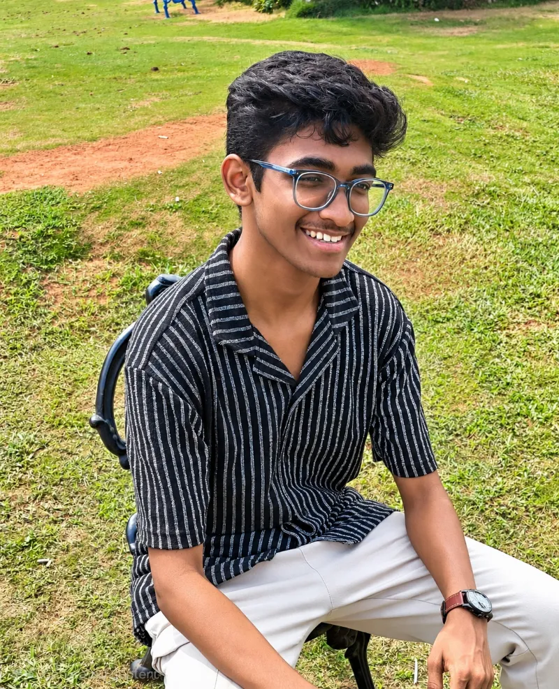 Adithya Kintali smiling outdoors, wearing glasses and a striped shirt
